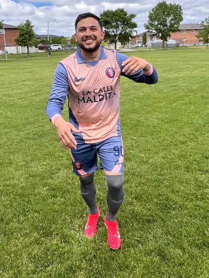 Christian Lopez, centrocampista de La Calle Maldita, con el uniforme salmón del equipo en una cancha de pasto